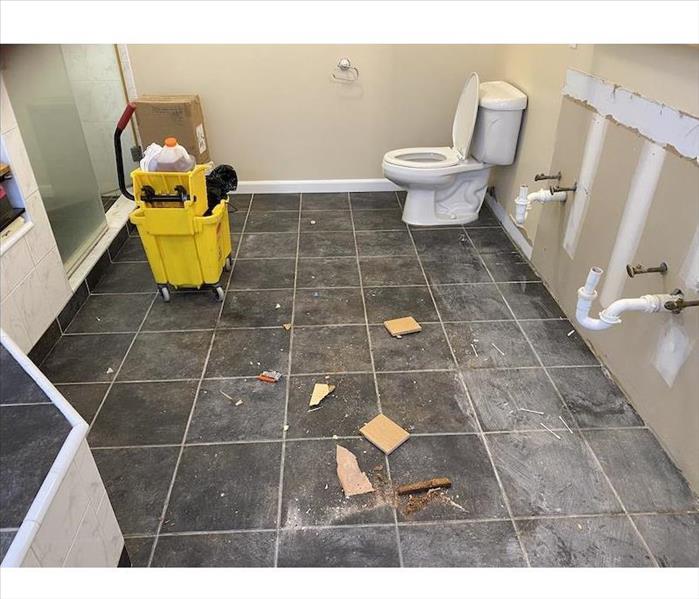 Bathroom with debris on the tile floor bare wall