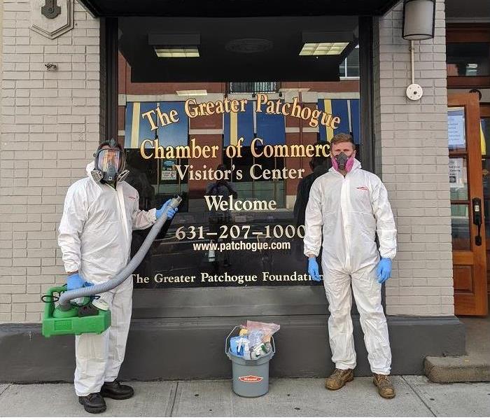 SERVPRO techs, donned with PPE and holding sanitizing equipment, standing in front of Chamber of Commerce 