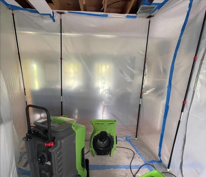 SERVPRO green air movers and a low-grain refrigerant dehumidifier in a sealed portion of an open floor plan living room with 
