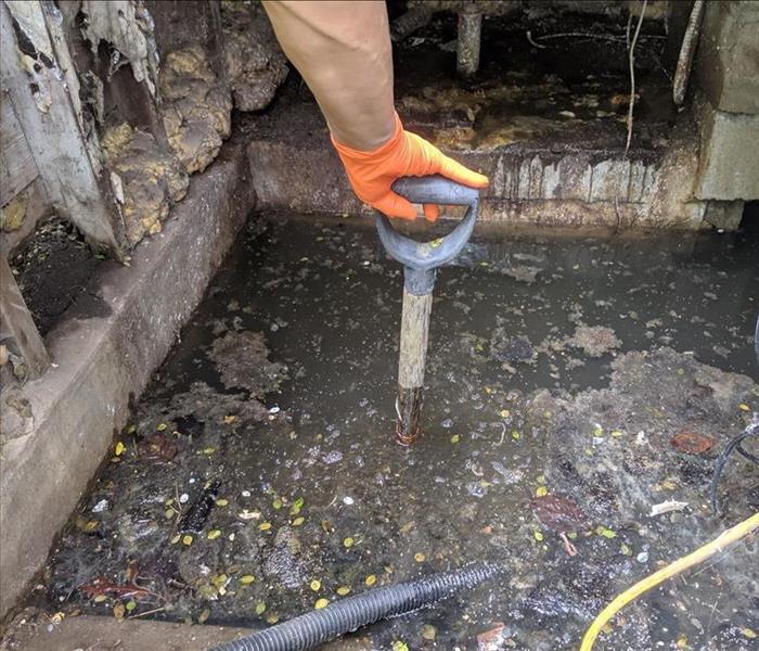  SERVPRO tech with shovel in deep water