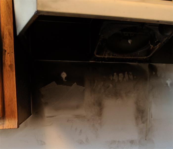 soot stained kitchen exhaust hood and damaged wood cabinet