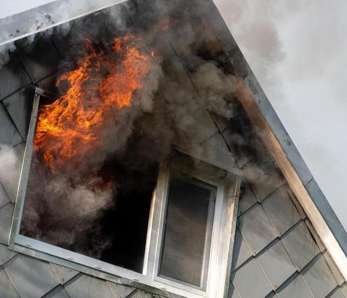 House with a fire in the attic coming out of broken windows